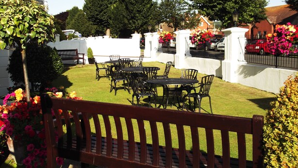 A courtyard with a wooden bench, a round table with chairs, and a white fence. - The Devonshire Park Hotel (Eastbourne)