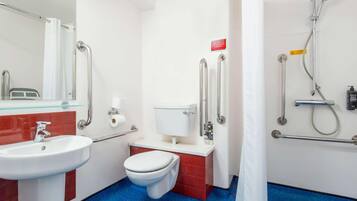 A bathroom with a sink, toilet, and shower area, equipped with handrails and a shower head.