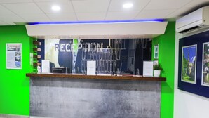 A reception desk with a green wall and a blue accent wall. - Ibis Budget Lancaster Centre (Lancaster)