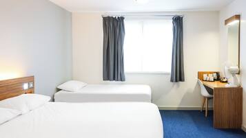 Habitación de hotel con dos camas, un escritorio, una silla, un espejo y una ventana con cortinas.