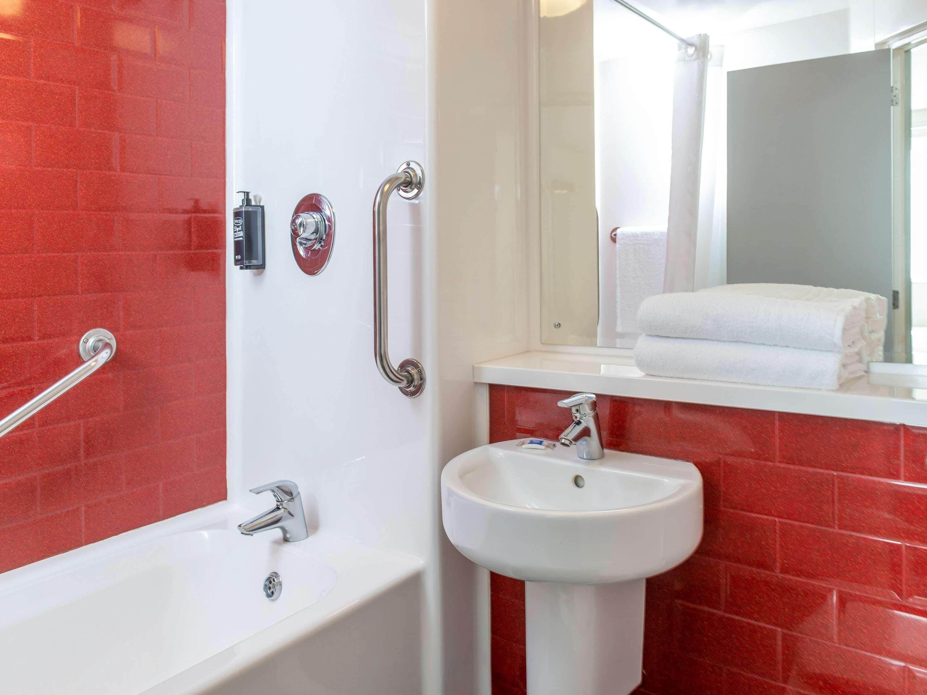Ein Badezimmer mit einer weißen Badewanne, einem Waschbecken und einem Spiegel.