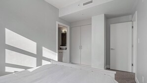 Ein Schlafzimmer mit Bett, Kleiderschrank und einem Badezimmer mit Waschbecken und Spiegel.
