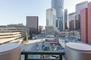 A cityscape with modern buildings, including a prominent TELUS building, and a parking lot with vehicles. - 2Bed + 2Bathroom apartment in downtown Urban Calgary (Calgary)