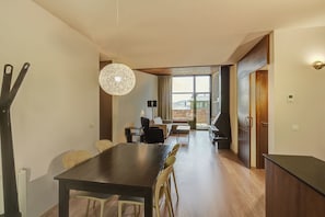 A modern living room with a dining area, large windows, and a view of the outdoors. - Apartments Masella 1600 Turistics (Alp)
