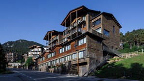 Un edificio de varios pisos con balcones, una escalera y vistas a una montaña.