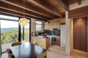 A modern kitchen with a dining area, large windows, and a view of the outdoors. - Apartments Masella 1600 Turistics (Alp)