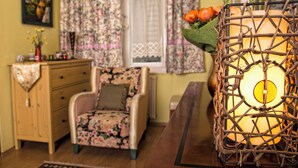 A cozy room with a wooden dresser, a floral-patterned armchair, and a woven lamp. - Theaterland Classic Apartments (Budapest)