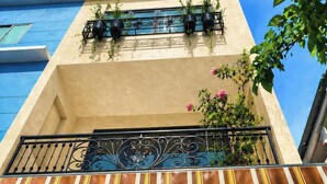 Un bâtiment doté d’un balcon, d’une fenêtre avec une porte en bois et d’une plante sur le balcon.