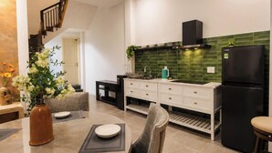 Une cuisine moderne avec un coin repas, comprenant un escalier, un réfrigérateur noir et un revêtement mural vert.