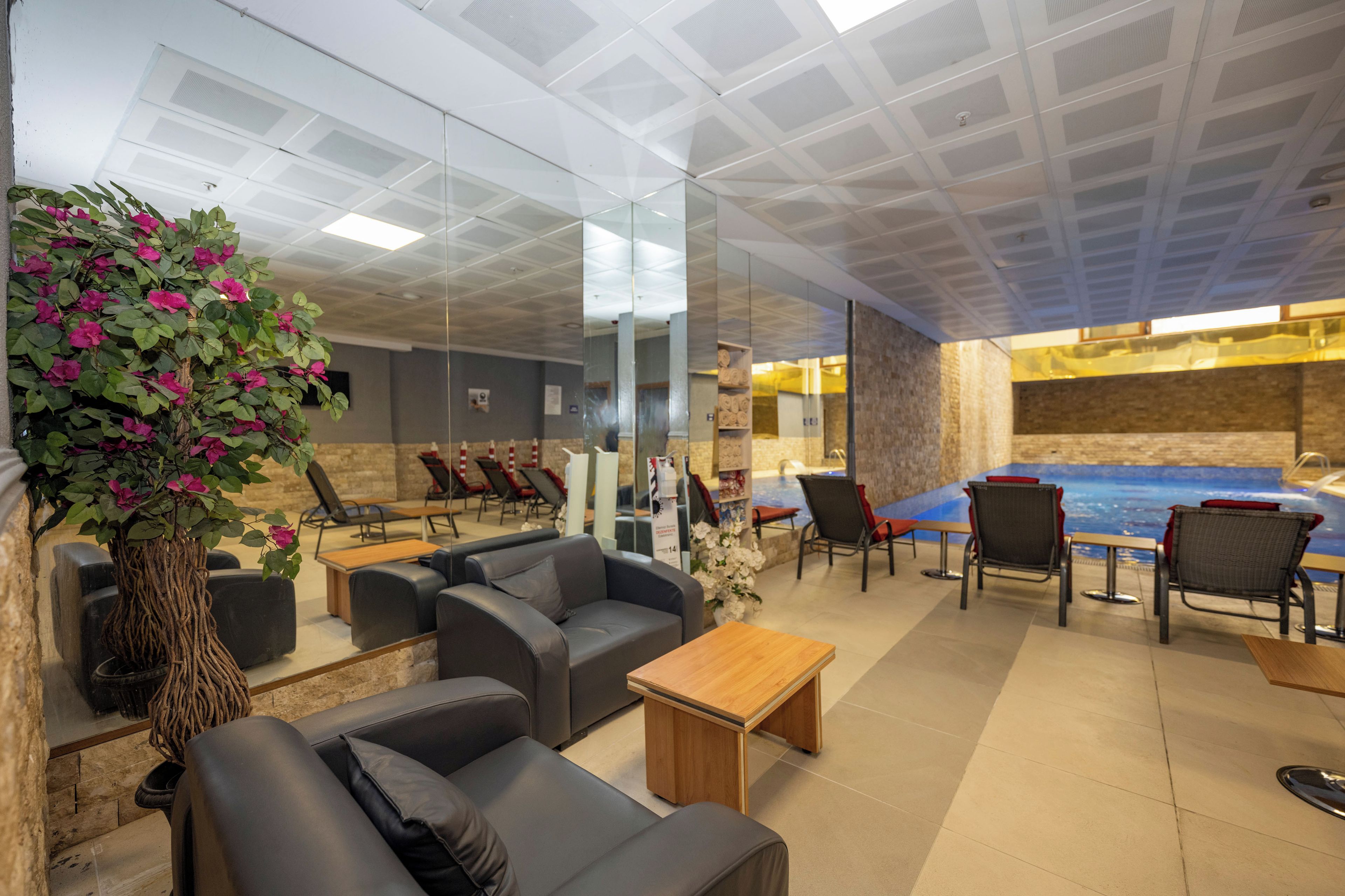 Un salón moderno con sofás de cuero, una mesa de centro de madera y un espejo grande que refleja el ambiente.