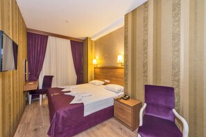 A hotel room with a bed, a desk, a chair, a TV, and a nightstand. - Harmony Hotel (Istanbul)