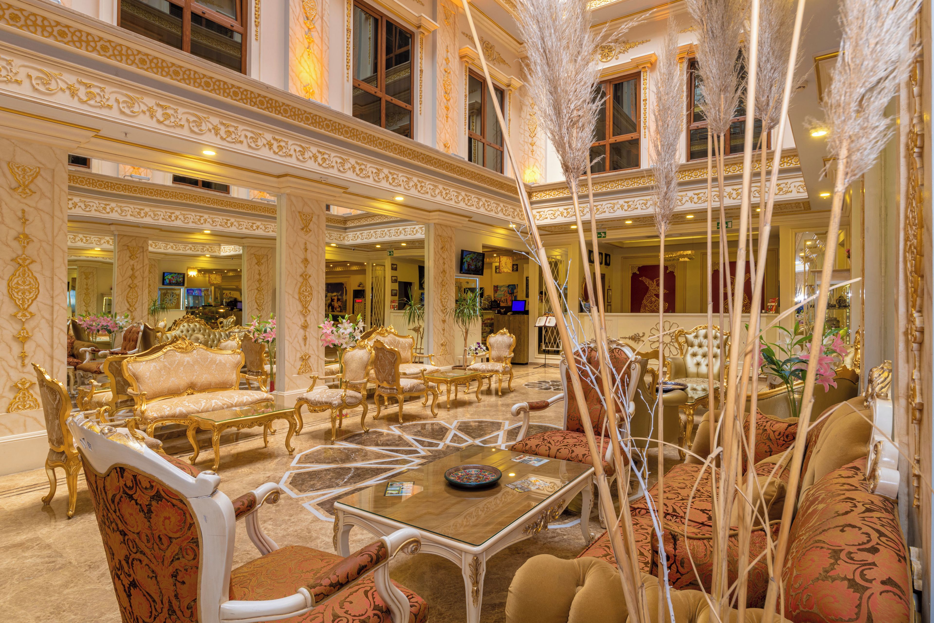 Un lobby de hotel lujoso con decoración elaborada, varias zonas de estar y una mesa de centro.