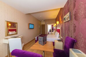 A hotel room with a bed, a desk with a computer, a chair, a purple sofa, and a mirror. - Harmony Hotel (Istanbul)