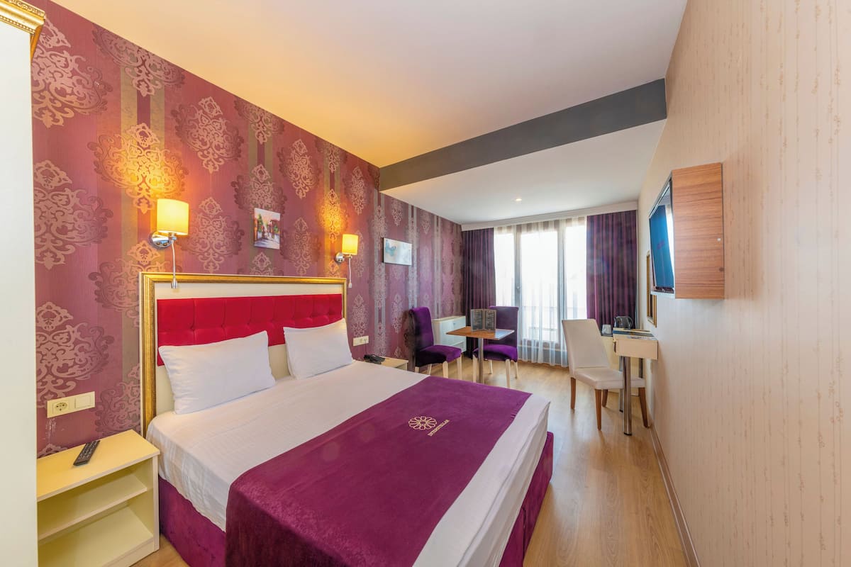Una habitación de hotel con una cama grande, un escritorio, una silla y una televisión.