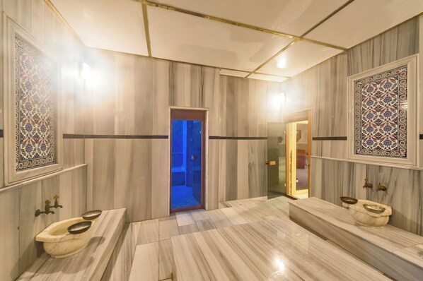 Baño con pisos de mármol, dos lavamanos y azulejos decorativos.