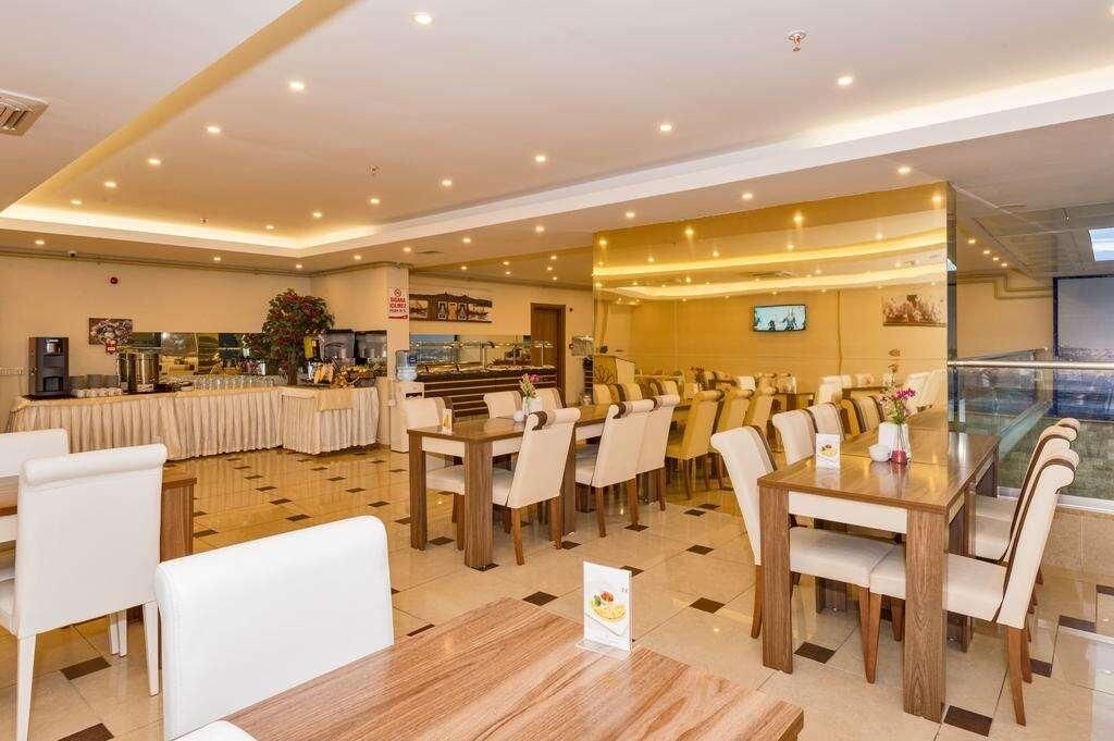 Un comedor de hotel con varias mesas y sillas, una mesa de buffet y una pantalla de televisión.
