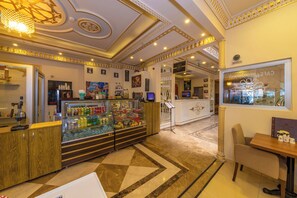 A hotel lobby with a reception desk, a glass display case with snacks, a seating area, and a decorative ceiling. - Harmony Hotel (Istanbul)