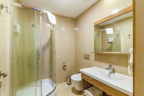 Un baño con ducha envuelta en vidrio, inodoro, lavamanos y espejo.