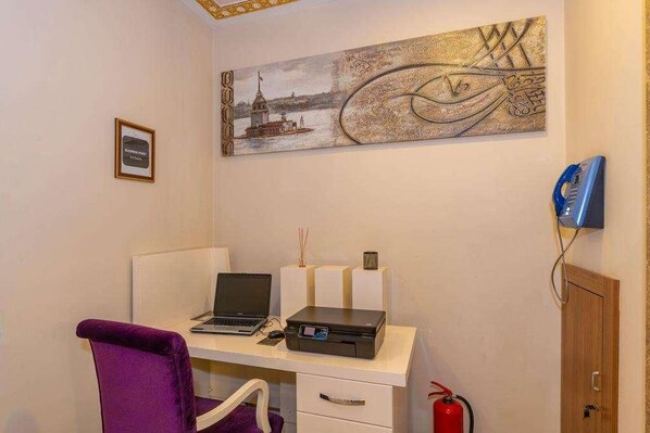 A room with a desk, a laptop, a printer, a purple chair, a wall-mounted telephone, and a fire extinguisher. - Harmony Hotel (Istanbul)