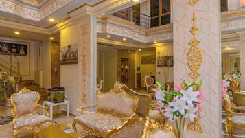 Een luxueus interieur met gedetailleerde gouden versieringen, comfortabele zitplaatsen en een decoratief aquarium.