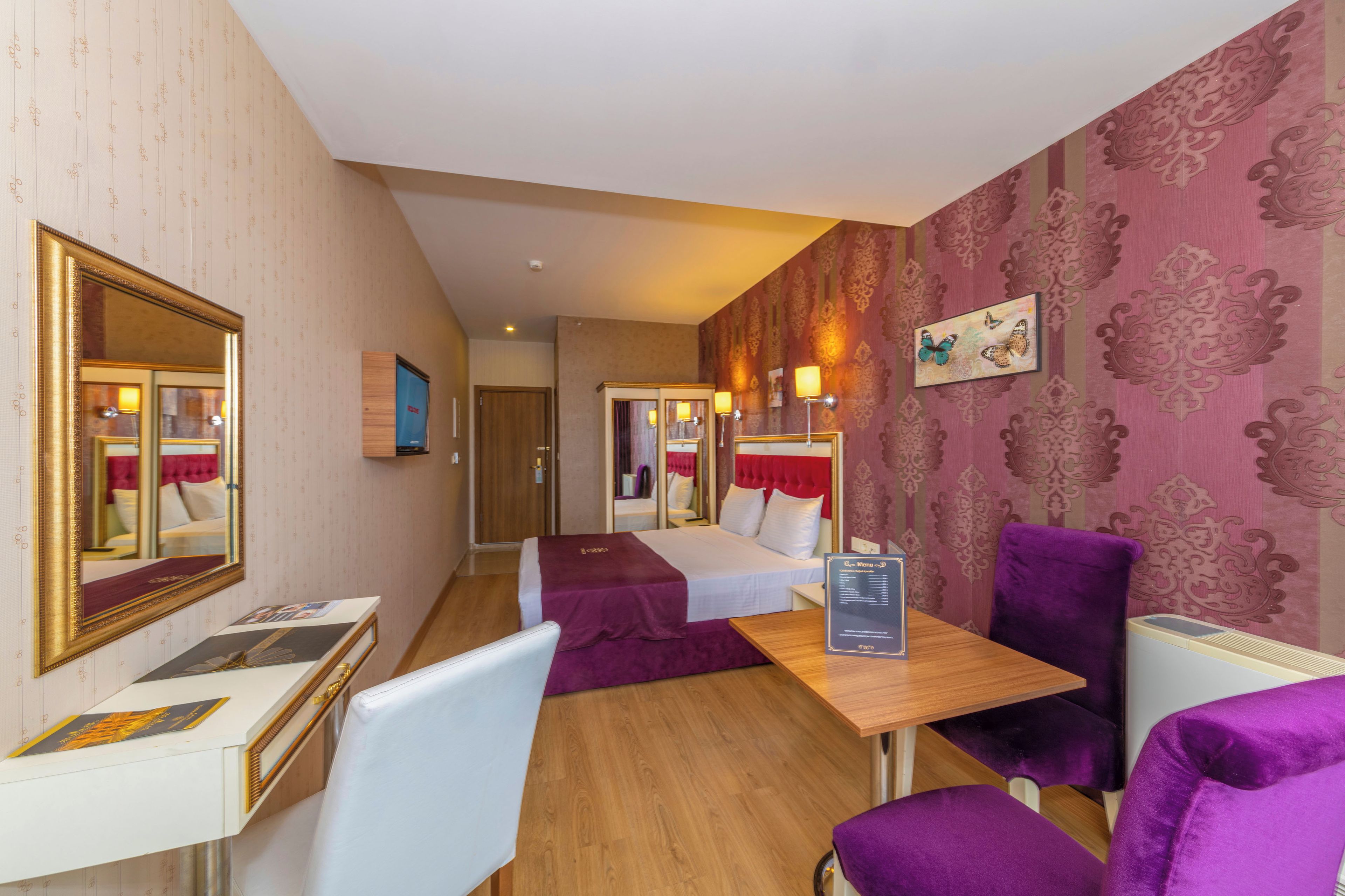 Una habitación de hotel con cama, escritorio, silla, mesa y espejo.