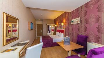 Una habitación de hotel con cama, escritorio, silla, mesa y espejo.