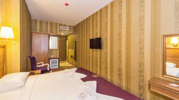 Ein Hotelzimmer mit Bett, Stuhl, Fernseher, Spiegel und Schreibtisch.