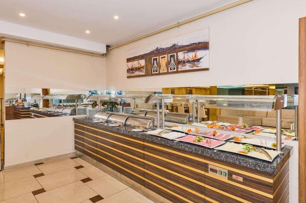 A buffet area with multiple food stations, a counter with a glass display, and a wall-mounted artwork depicting a coastal scene.