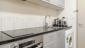 Eine kompakte Küche mit Edelstahlbackofen, integriertem Waschmaschine und Spüle.