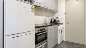 Eine kompakte Küche mit Kühlschrank, Backofen, Mikrowelle, Spüle und Waschmaschine.