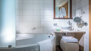 A bathroom with a bathtub, a sink, a mirror, and a towel rack.