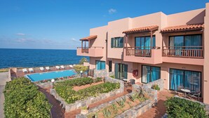 A hotel with a pool, outdoor seating, and a view of the sea.
