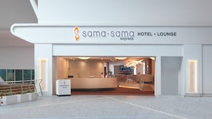 A modern hotel lobby with a reception desk, seating area, and a staircase leading to an upper level. - Sama-sama Express Klia 2 (Sepang)