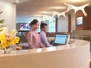 A reception desk with a computer, a TV screen, and a modern ceiling design. - Sama-sama Express Klia 2 (Sepang)