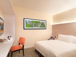 A hotel room with a bed, a desk with a chair, a painting on the wall, and a nightstand with a lamp. - Sama-sama Express Klia 2 (Sepang)