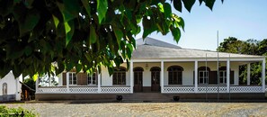 A colonial-style building with a white facade, arched windows, and a covered porch. - Roça Sundy Hotel (Príncipe Island)