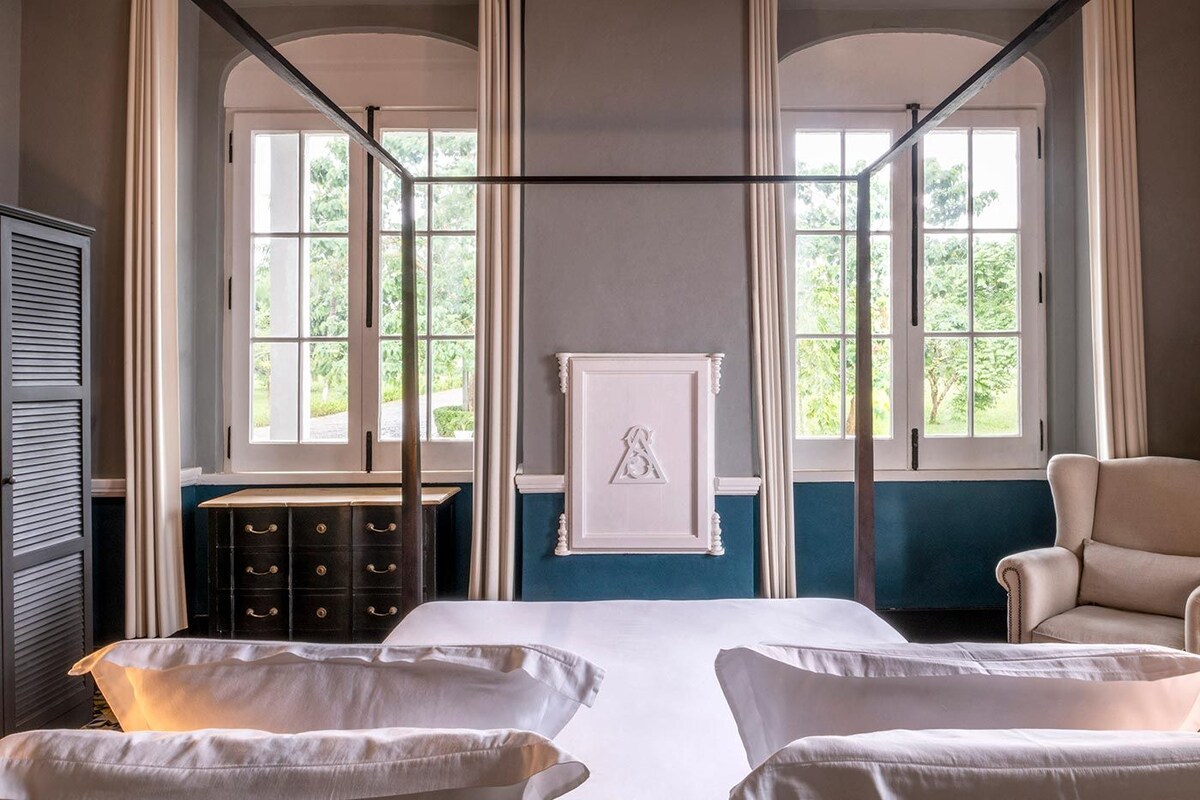Una habitación con una cama, dos sillas, un aparador y un cuadro en la pared.