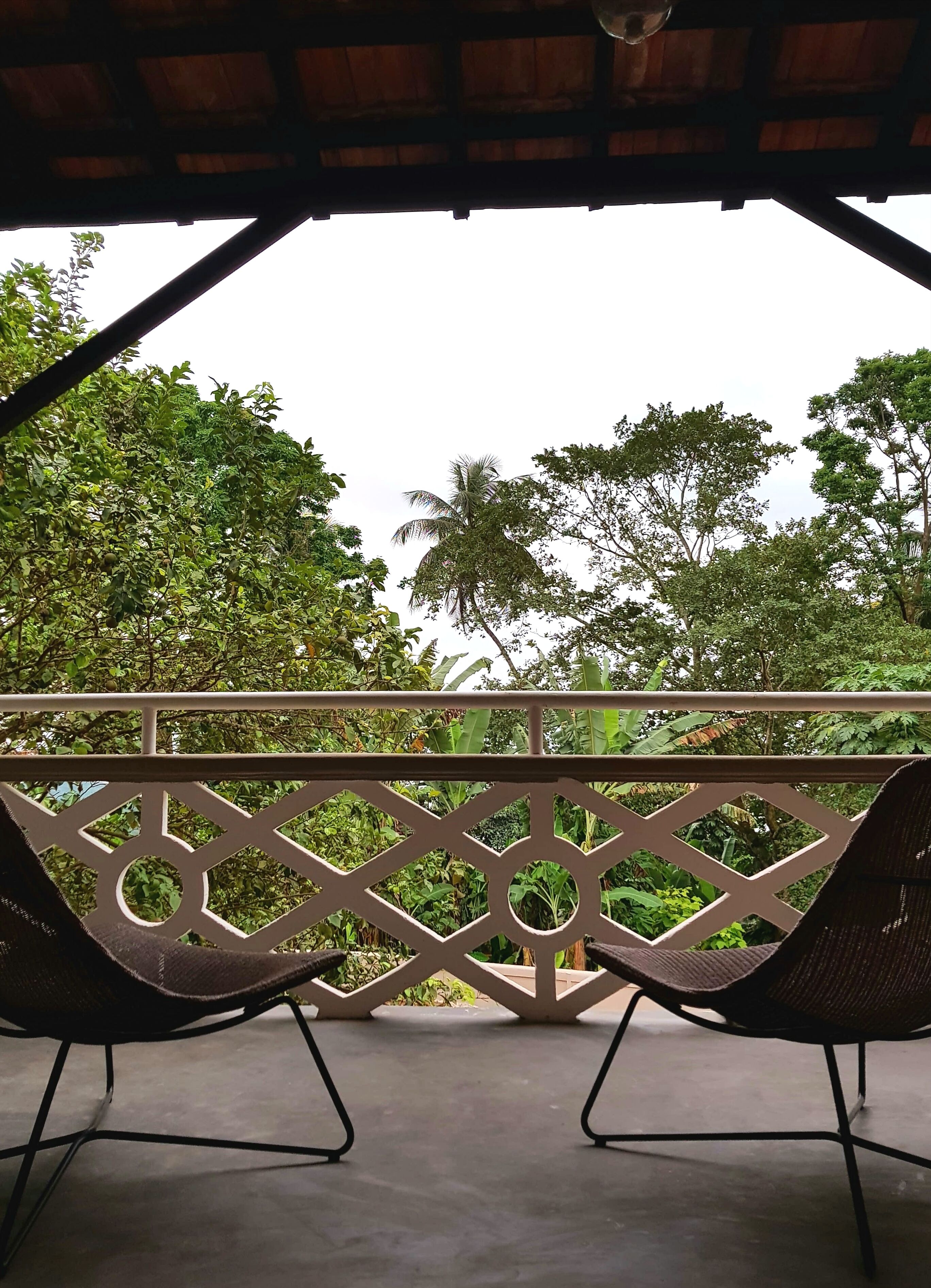 A covered outdoor seating area with a view of lush greenery and trees.
