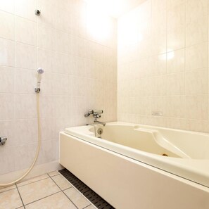 Un baño con bañera, cabezal de ducha y desagüe.