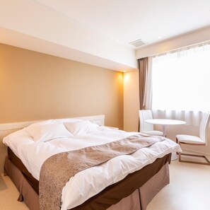 Una habitación de hotel con cama, una silla, una mesita y una ventana con cortinas.
