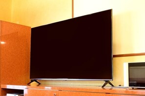 Ein Fernseher auf einem Schrank in einem Zimmer mit einem Holzschrank und einer Wand mit Lichtschalter.
