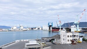 A harbor with industrial buildings, cranes, and a large ship docked. - Hotel Vega Takamatsu (Takamatsu)