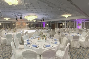 A banquet hall with round tables, white chairs, and chandeliers. - Gewan Hotel Cairo (Giza)