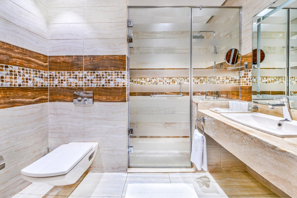 A modern bathroom with a glass shower enclosure, a toilet, and a sink with a mirror.