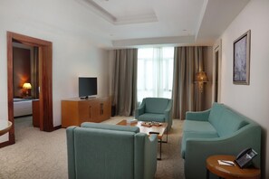 Ein Hotelzimmer mit einer Couch, einem Sessel, einem Fernseher und einem kleinen Tisch.