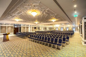 A conference room with rows of chairs, a podium, and ornate ceiling details. - Gewan Hotel Cairo (Giza)