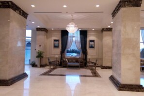 A spacious lobby with a chandelier, a sofa, and a large window with curtains. - Gewan Hotel Cairo (Giza)