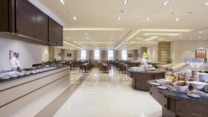 A spacious hotel dining area with multiple tables and a buffet setup. - Gewan Hotel Cairo (Giza)