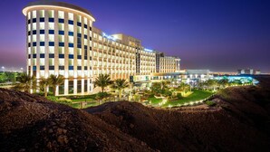 A large hotel with a curved facade, multiple floors, and a well-lit exterior.