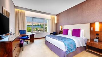 Una habitación de hotel con una cama, un escritorio, una silla y un televisor.